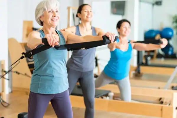 Toning Arms After 60: Empowering Womens Fitness Through Effective Weight Training 2 older woman doing weight training Chelmsford and resistance in the gym to tone upper arms